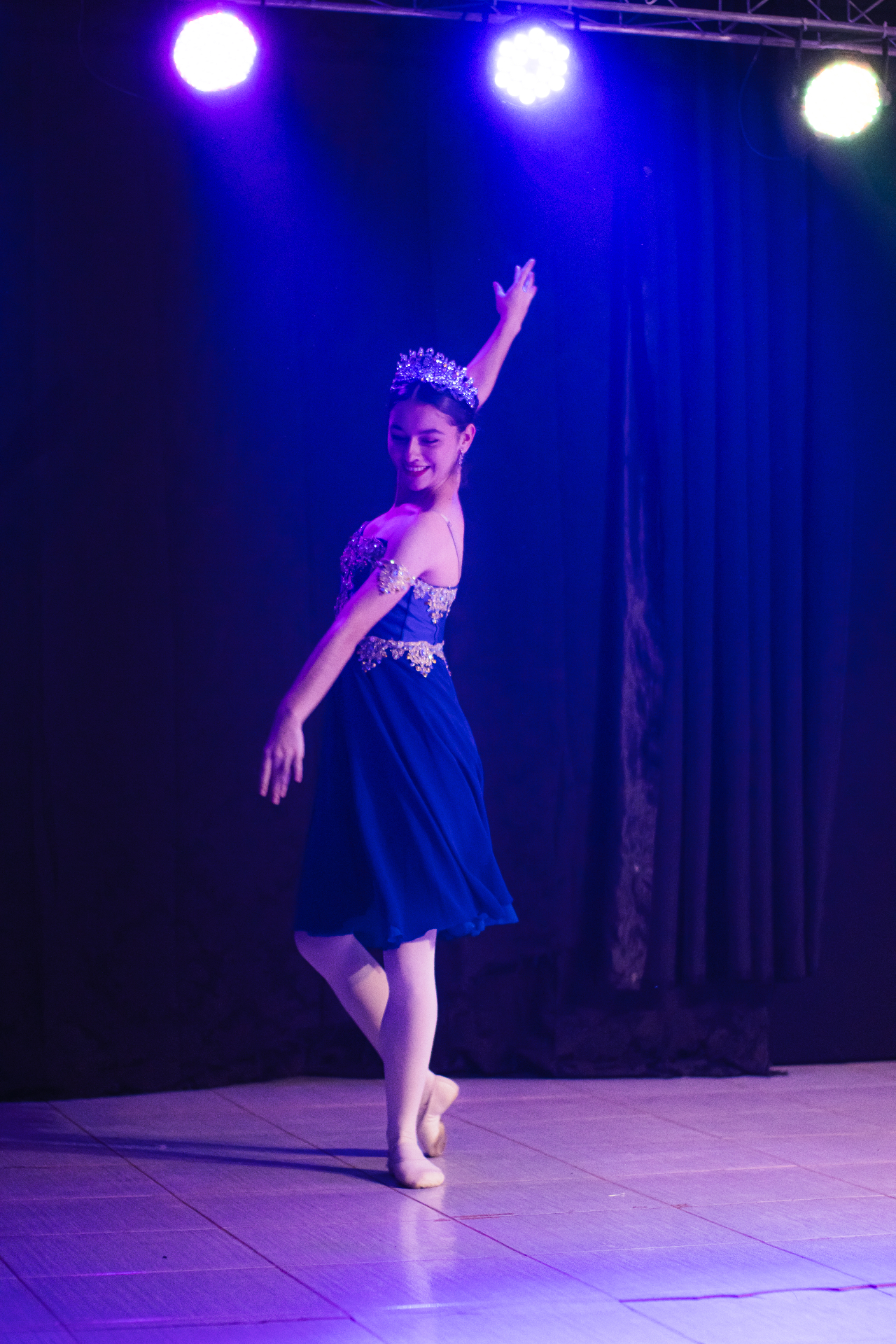 Bailarina em vestido azul e coroa brilhante apresentando balé clássico no palco do 1º Sarau Cultural Caminhos do Vale